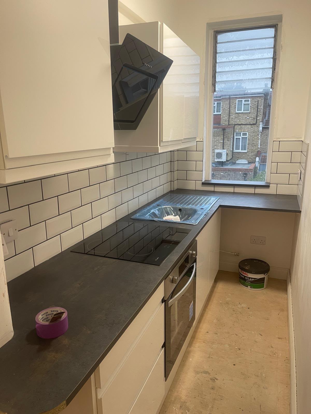 Galley kitchen after fit-out, subway tile splashback and finished units