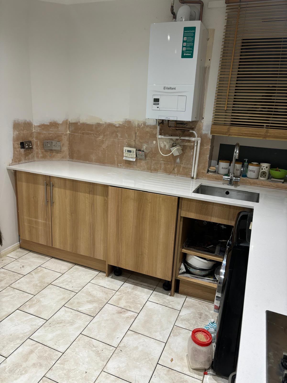 Kitchen before renovation, exposed boiler and bare walls